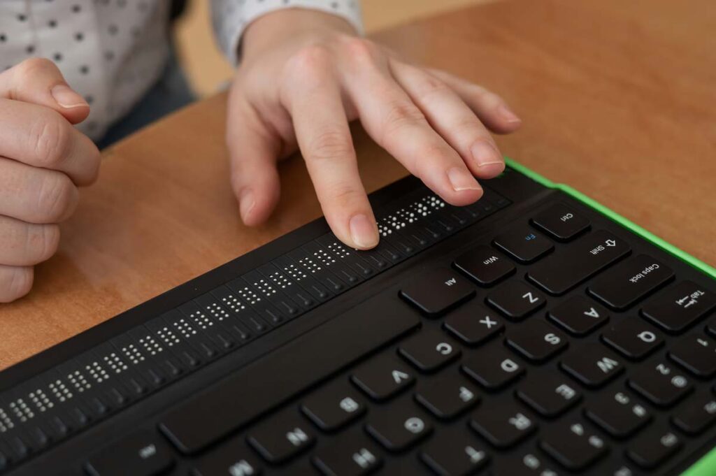 Close up of a hand using a braille keyboard, representing the Stanley Steamer website class action.