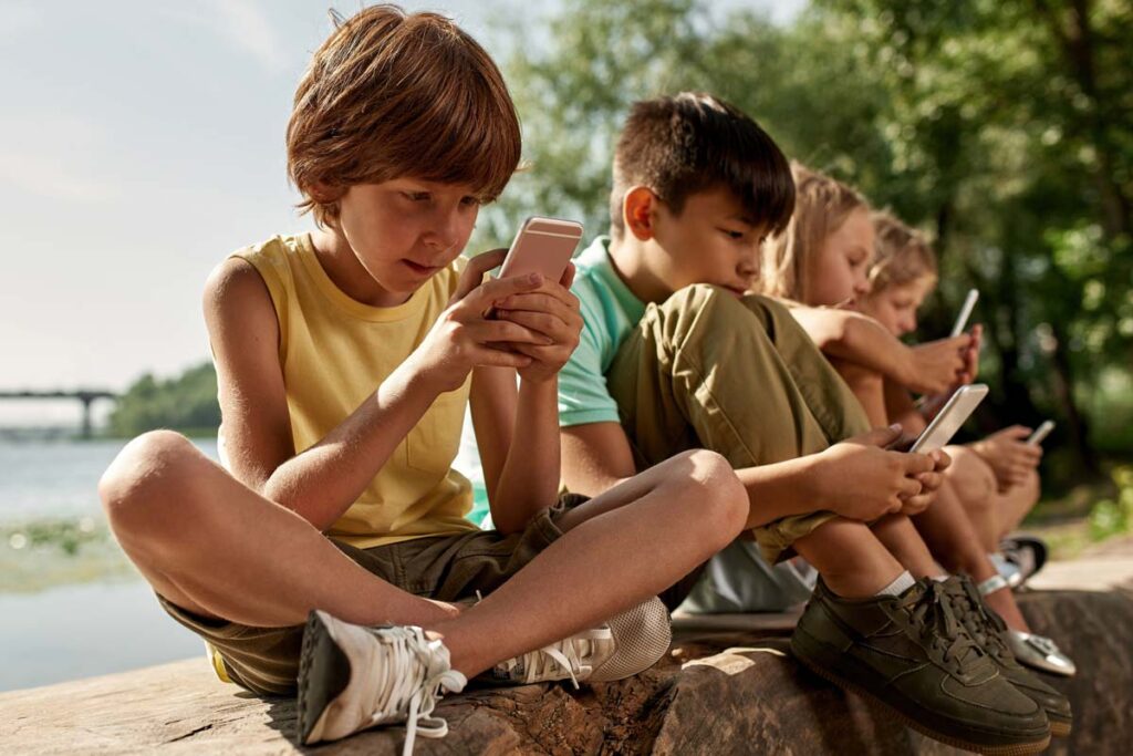 A row of kids using social media on their smartphones, representing the NY social media bills.
