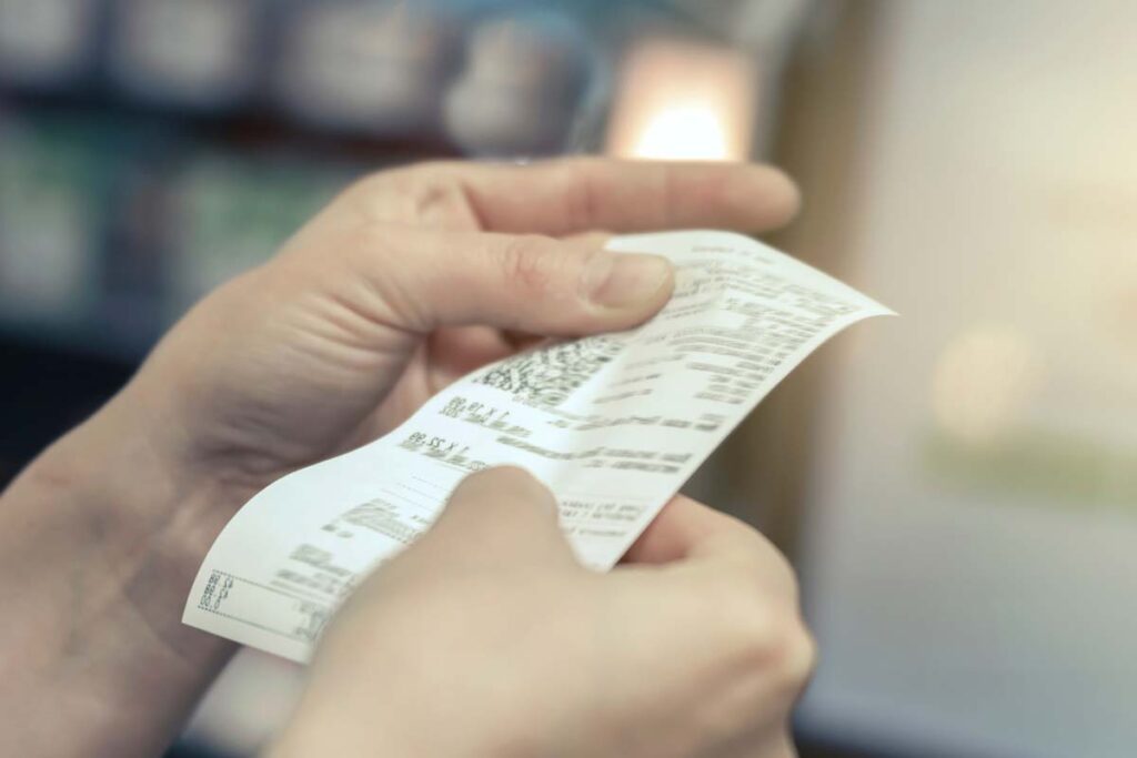 Close up of a hand holding a receipt, representing junk fees.