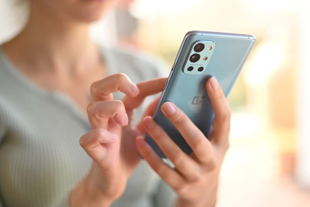 Close up of a womans hands using a OnePlus smartphone, representing the OnePlus 9 smartphone settlement.