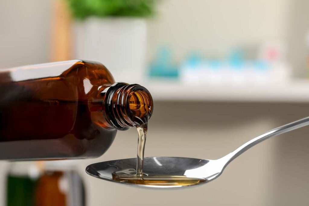 Close up of liquid medication being poured into a spoon, representing the Sucralfate recall.