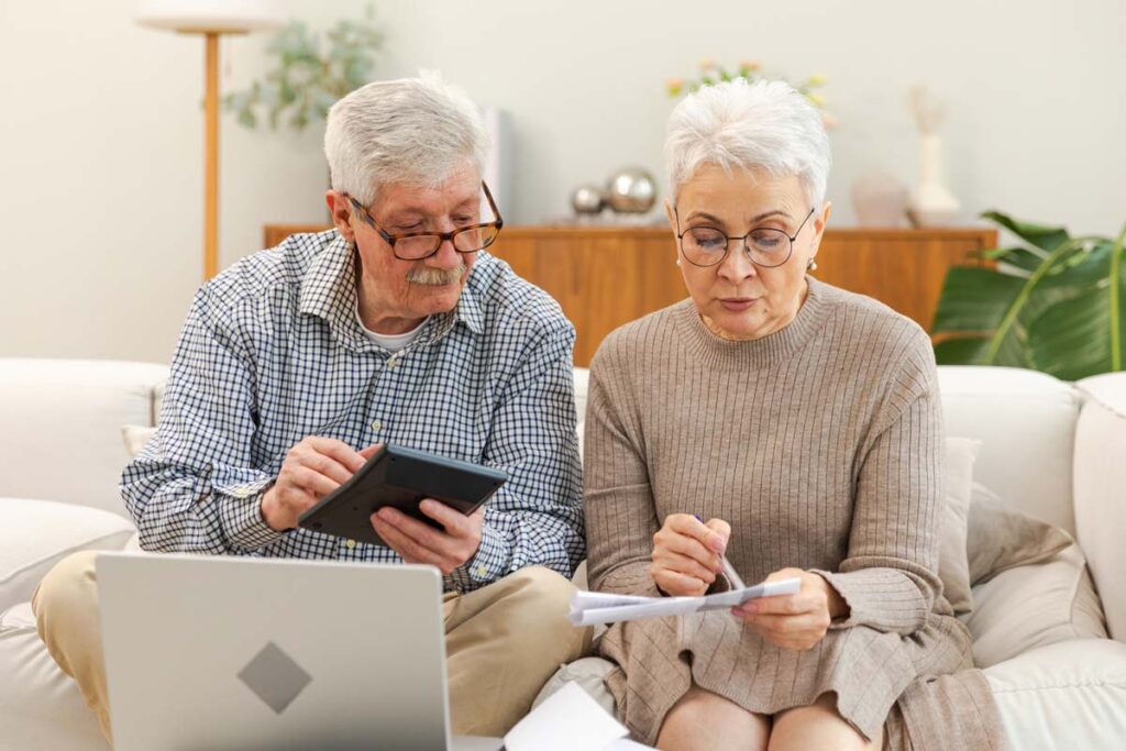 Elderly couple reading a letter and using a calculator, representing the Frontier-Mt. Carroll Mutual Insurance class action settlement.