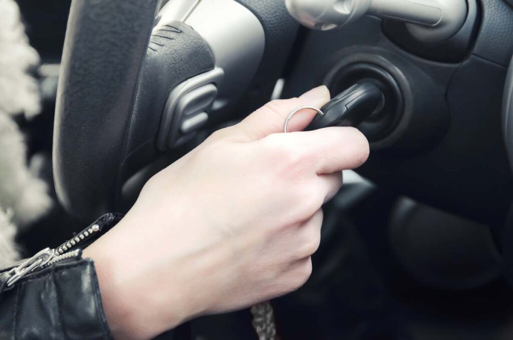 Close up of hand turning key on a car, representing September vehicle recalls.