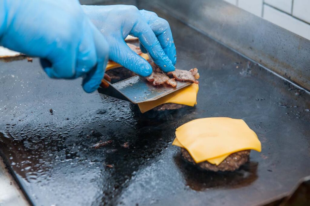 Close up of burger patties on a hot grill, representing the McDonald's/Wendy's burger size class action lawsuit.