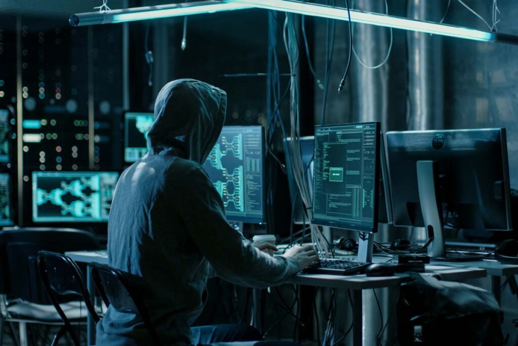 Back view of a hooded hacker using a computer, representing the Spear Wilderman data breach class action settlement.