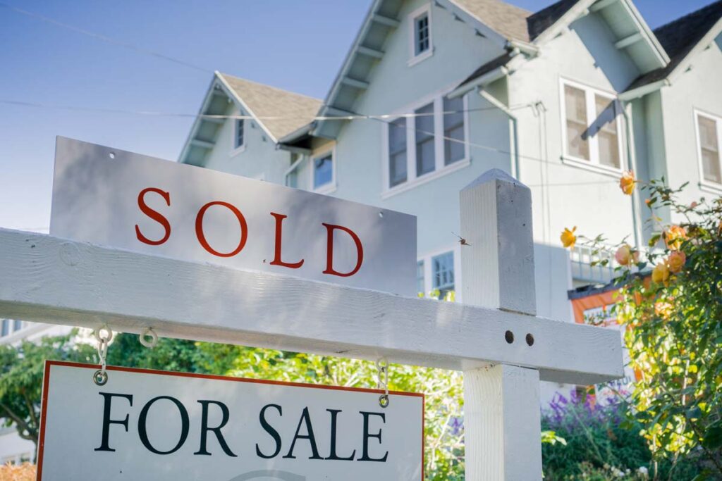 Close up of a sold sign atop a house for sale sign, representing the home seller commissions class action.