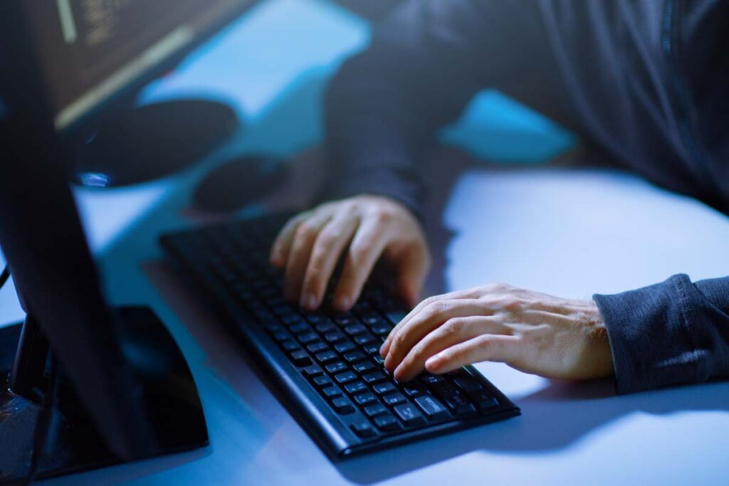 A cybercriminal typing on a computer keyboard, representing the Choice Health data breach class action lawsuit settlement.