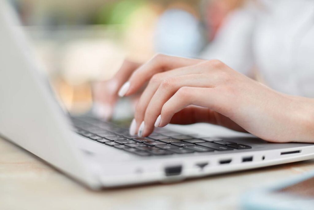 Close up of a woman's hands typing on a laptop, representing the Snap Finance data breach class action lawsuit settlement.