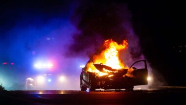 A car on fire with the police in the background, representing the NHTSA investigation into the Hyundai and Kia recalls.