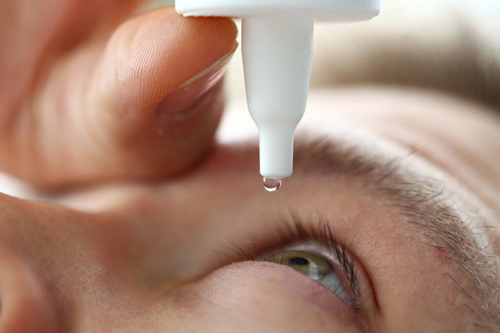 Close up of a man putting eyedrops in his eye, representing the CVS and Rite Aid eye drops recall.