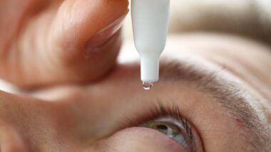 Close up of a man putting eyedrops in his eye, representing the CVS and Rite Aid eye drops recall.