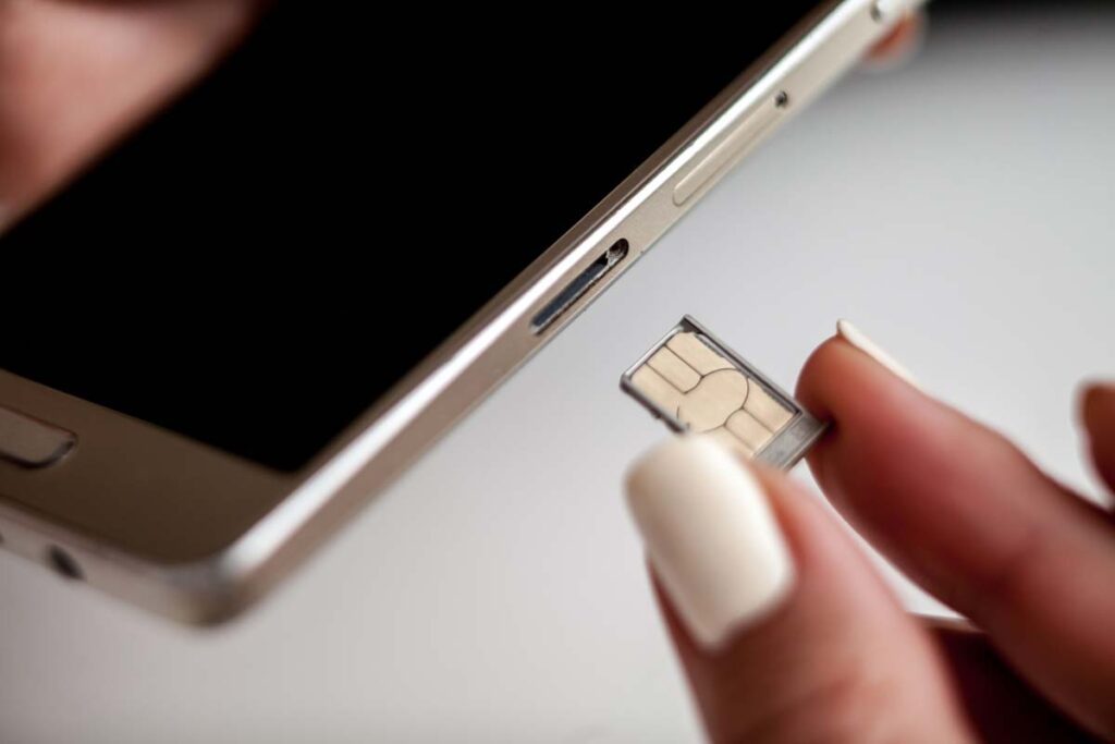 Close up of a woman putting a SIM card into her phone, representing the cell phone SIM card fraud rules.