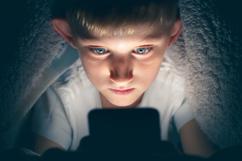 Close up of a young boy using a smartphone, representing AI and online protection recommendations for children.