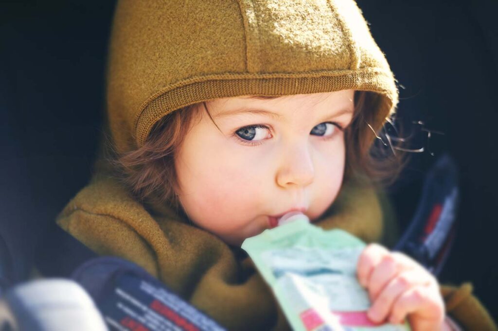 A young girl eating from a puree pouch, representing the FDA lead-in-applesauce investigation and WanaBana recall.