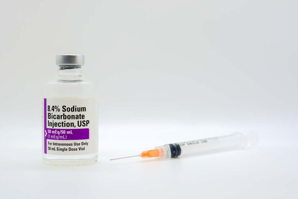Sodium Bicarbonate vial next to a medical syringe, representing the injection recall.