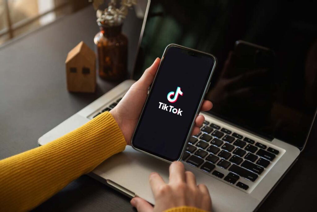 Close up of a woman holding her smartphone with the TikTok logo displayed, representing TikTok news.