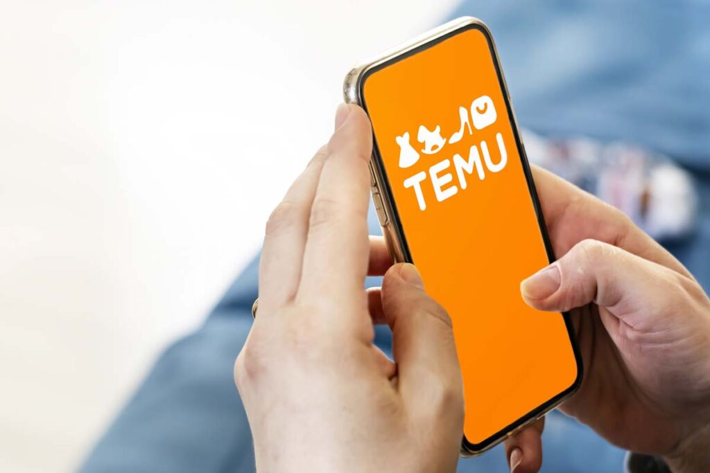 Close up of a woman holding a smartphone with the Temu logo displayed, representing recent Temu class action lawsuit claims.