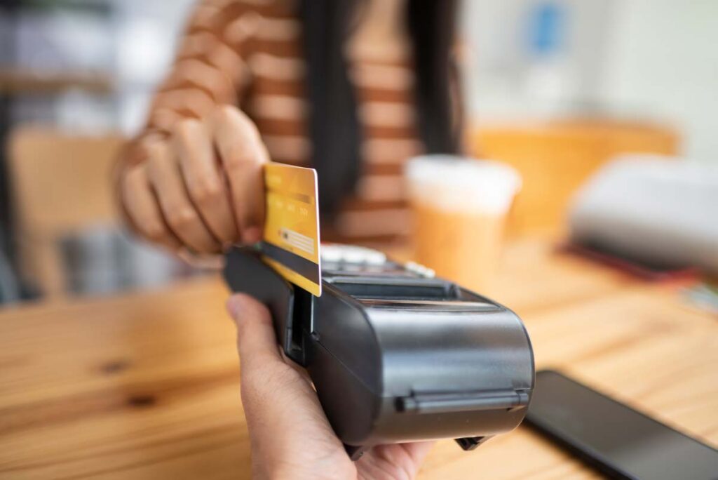 Close up of a debit card being swiped on a point-of-sale machine, representing the Pioneer Bank overdraft fees class action.