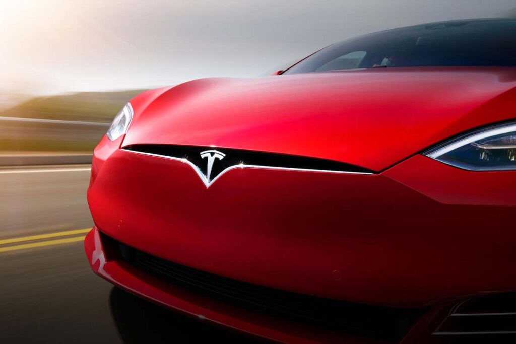 Front bumper of a Tesla driving along a road, representing the Tesla recall.