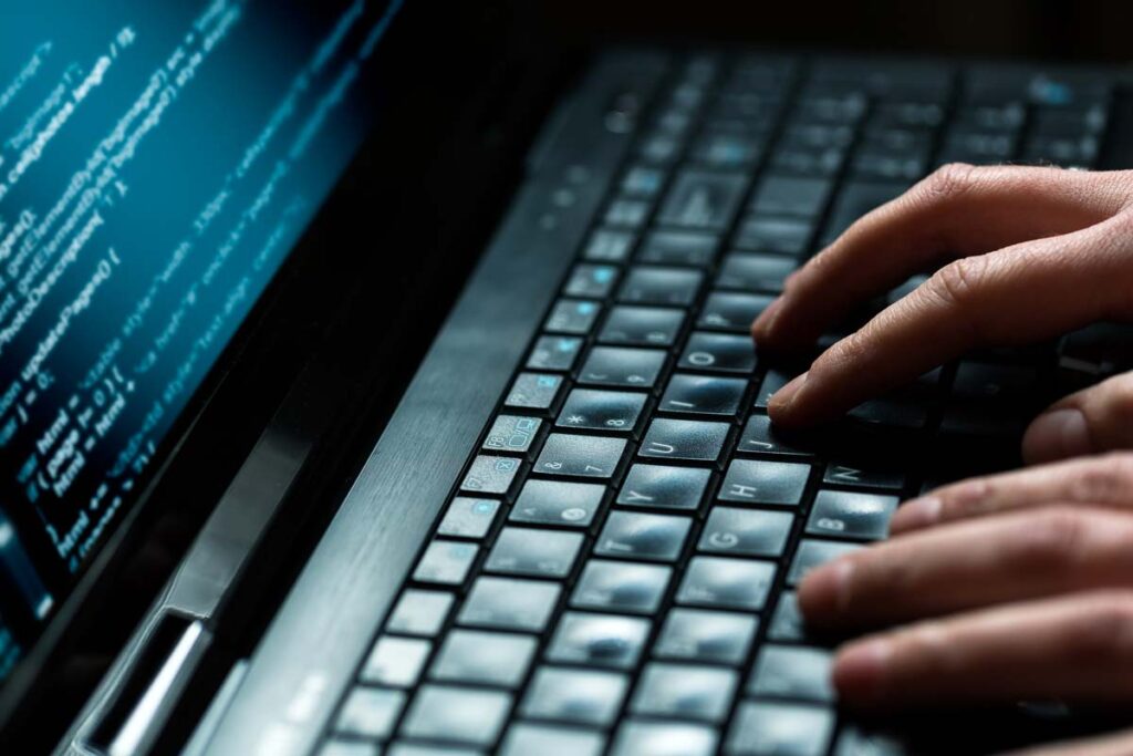 Close up of a hackers hands typing on a keyboard, representing the MedStar data breach class action settlement.