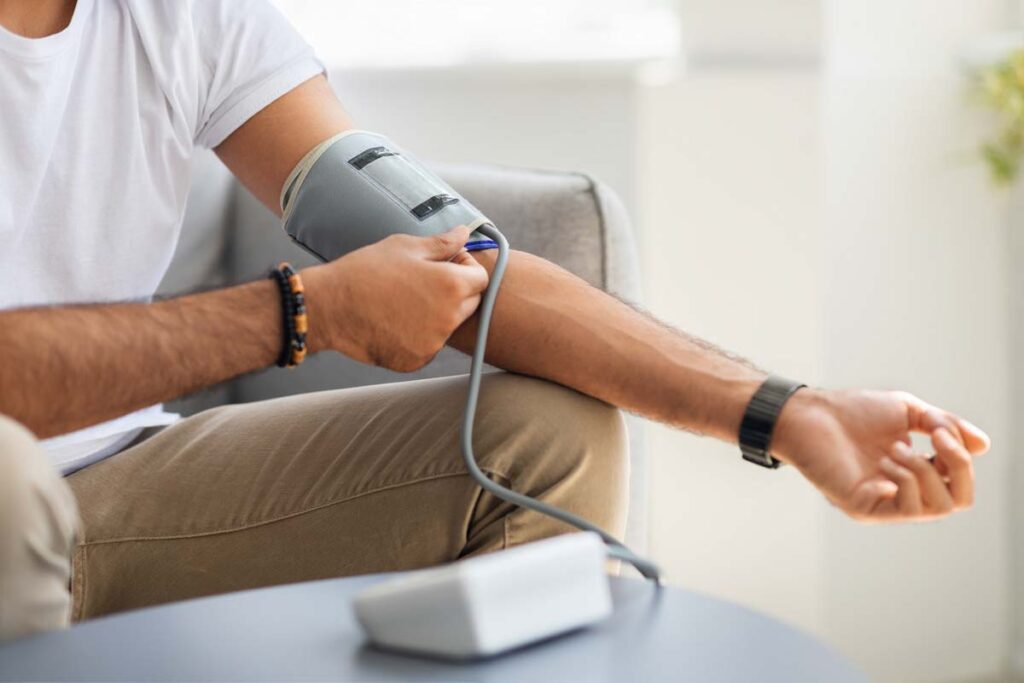 Close up of a man using a portable blood pressure monitor at home, representing the Equate blood pressure monitor class action.