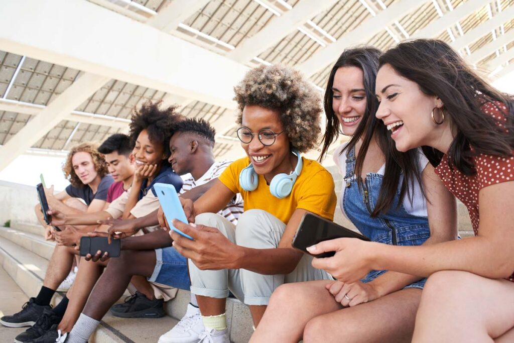 A group of teens looking at their smartphones, representing the YouTube, TikTok, Snapchat and Instagram teens survey.