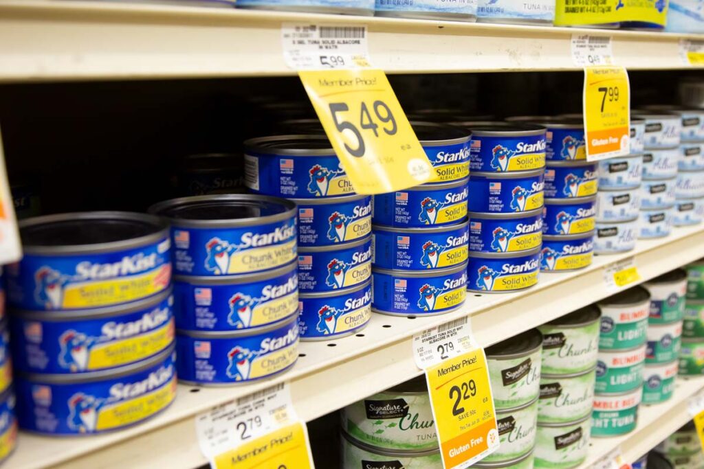 Closeup of canned tuna on a grocery store shelf, representing the Washington chicken and tuna price-fixing class action lawsuit settlement.