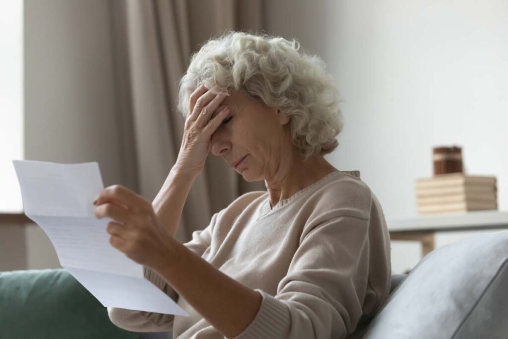 A stressed elderly woman reading a letter, representing the Humana class action lawsuit.