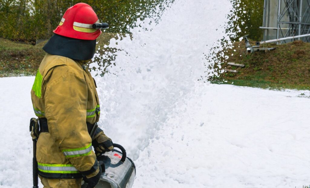 A firefighter in protective clothing extinguishes the fire by feeding foam.