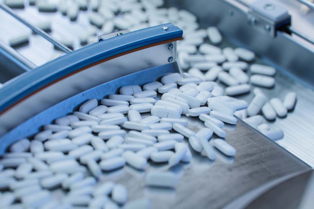 Close up of pills being manufactured, representing the new federally funded drugs patents policy.