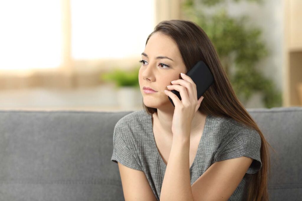 Serious woman listening to a robocall on her phone, representing the Sovereign Lending Group TCPA class action settlement.