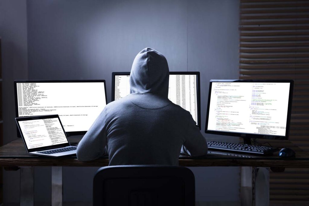 Rear view of a hooded hacker using a computer, representing the Akumin Corp. data breach class action lawsuit.