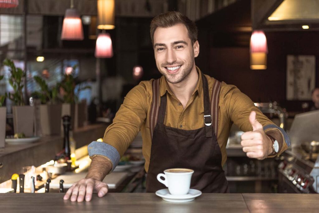 A coffee shop employee giving a thumbs up while working, representing the minimum wage raise.