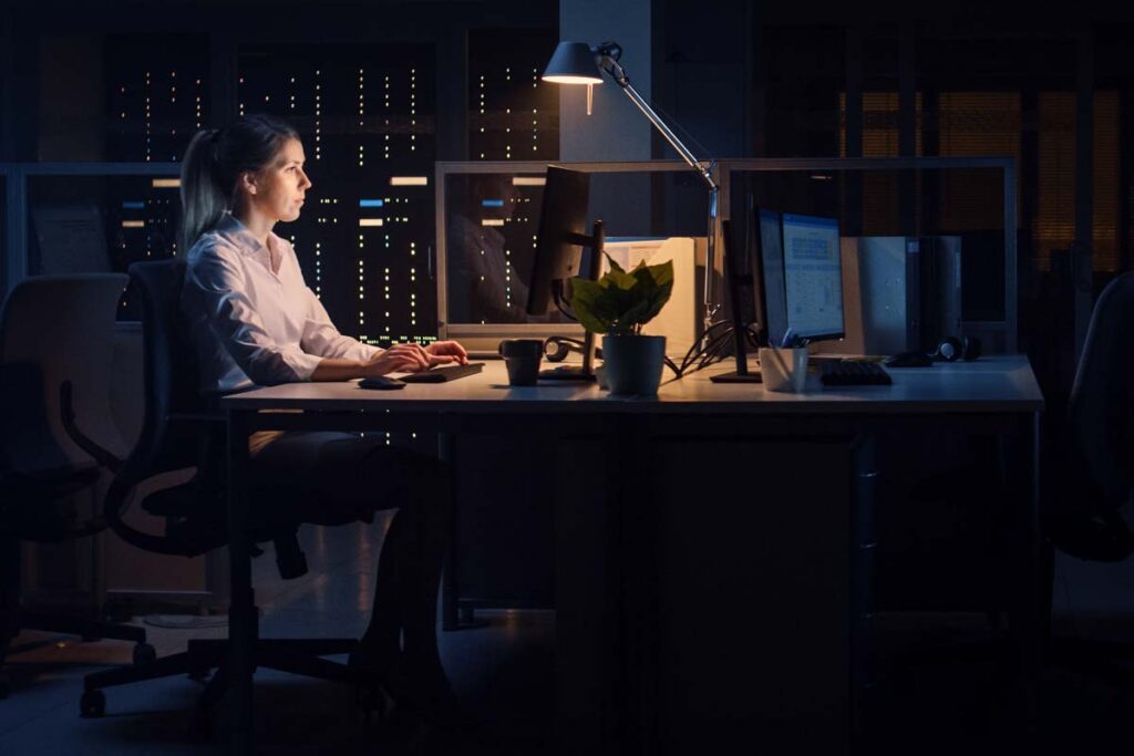 A female worker working in an office at night, representing the Dimension Development Co. class action lawsuit settlement.