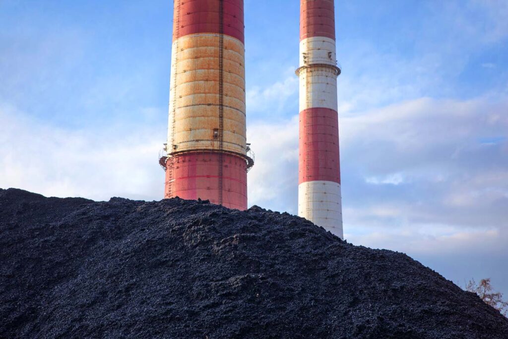 Coal in front of coal plant chimneys, representing the Hilco Redevelopment class action settlement.