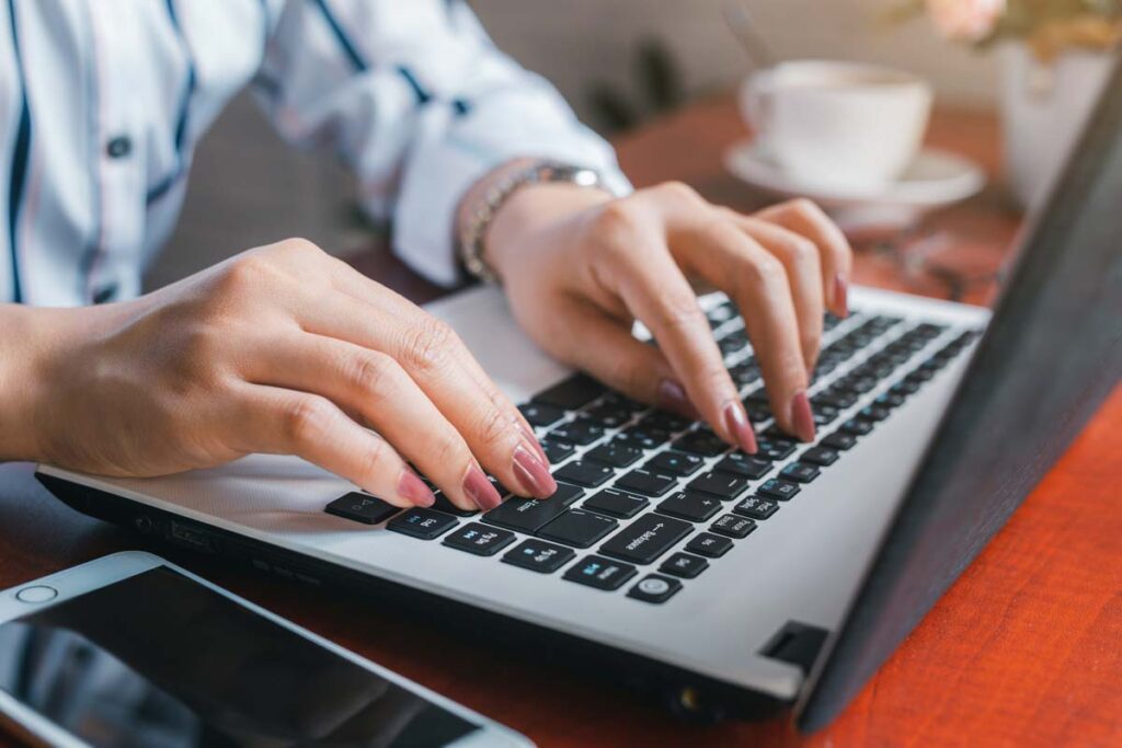 Close up of a woman's hands typing on a laptop, representing the Blackhawk Newtwork data breach class action lawsuit settlement.