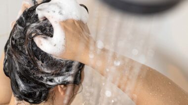 Woman lathering her hair with shampoo in the shower, representing the Neutrogena shampoo class action.