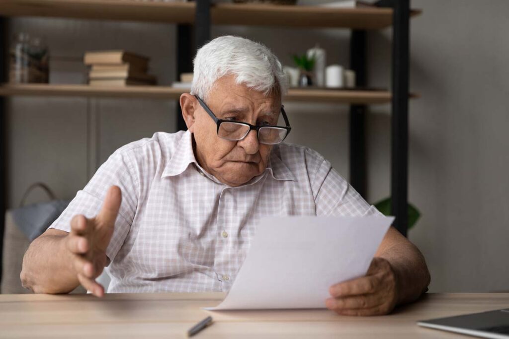 Elderly man looking at a document with concern, representing the CIC Mortgage Credit settlement.