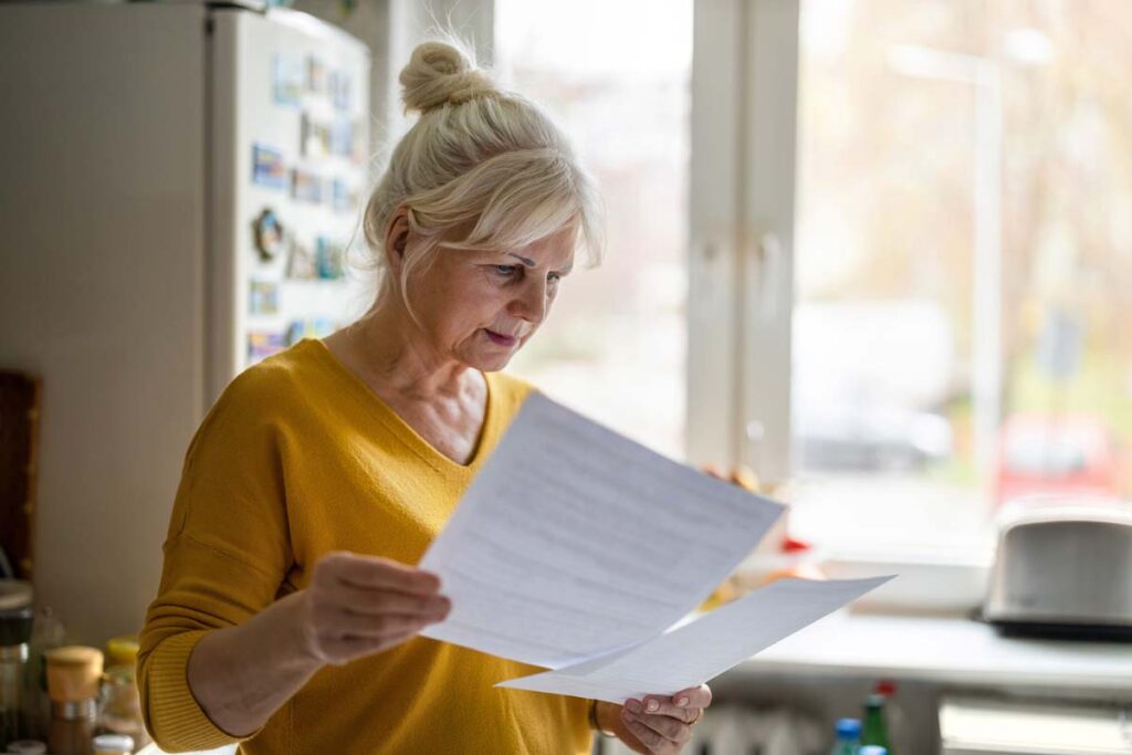 An elderly woman reading documents regarding her 401k plan, representing the NCL Corp. 401(k) class action settlement.