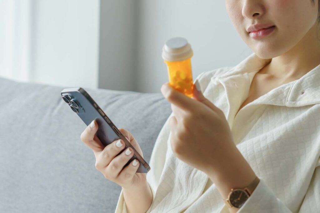Close up of a woman refilling her prescription using her smartphone, representing the Postmeds data breach class action.