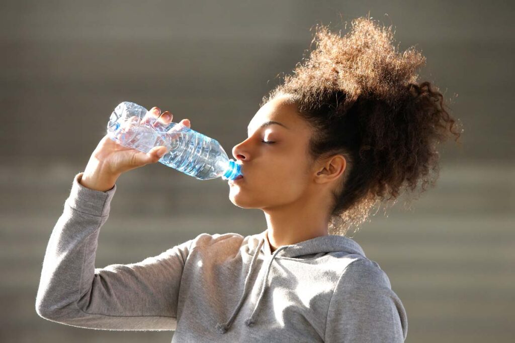 A woman drinking from a water bottle, representing the Real Water liver failure trial.