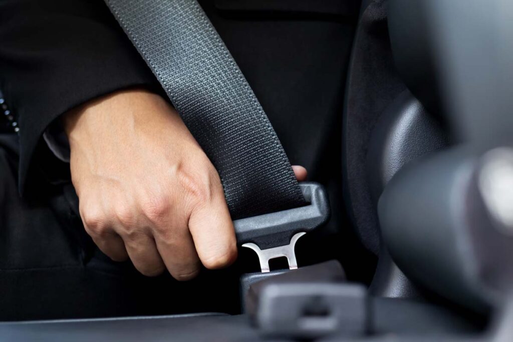 Close up of a hand clicking in a seat belt, representing the Ford recall.