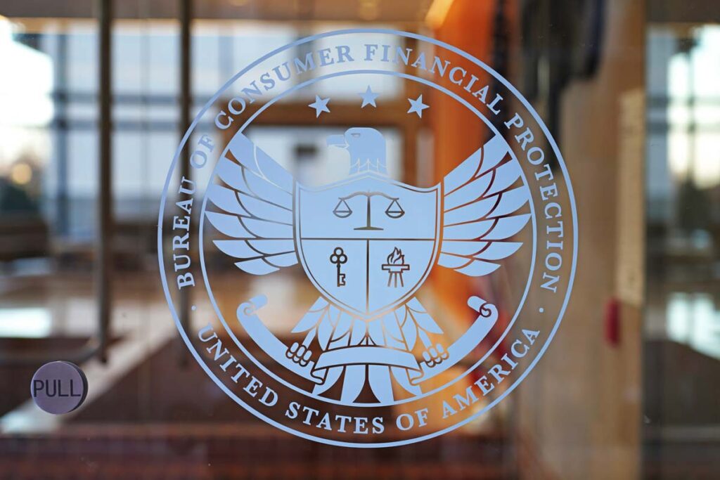 Close up of Consumer Financial Protection Bureau seal on a glass entrance door, representing the CFPB discrimination class action lawsuit settlement.