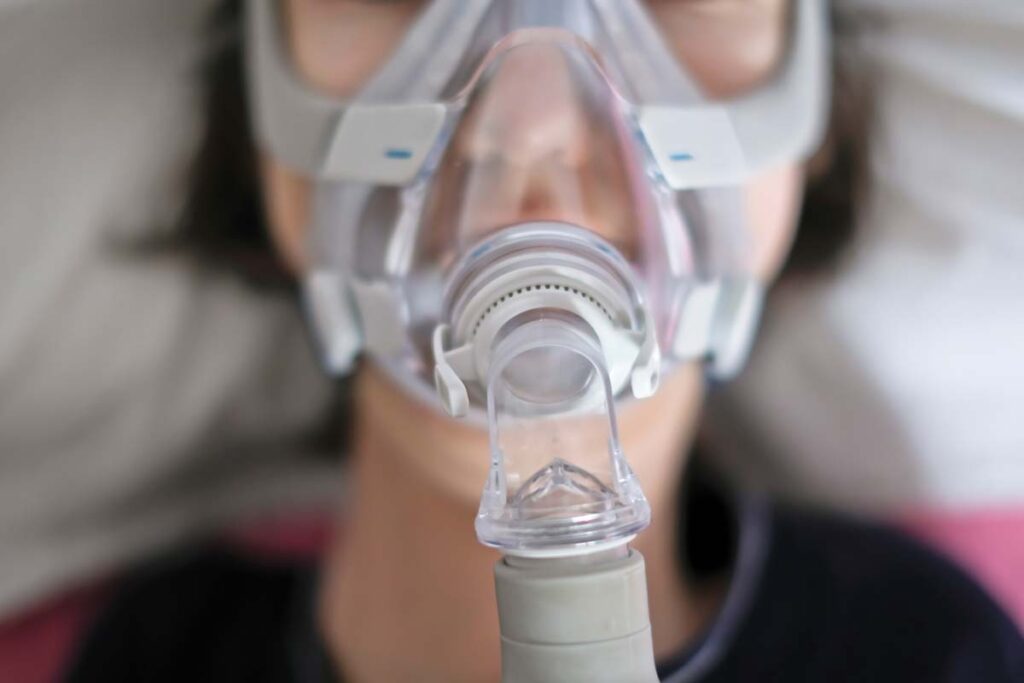Close up of a woman sleeping while wearing a CPAP mask, representing Philips CPAP and BiPAP machines.