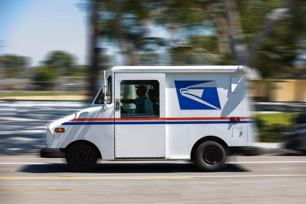 A USPS worker driving a USPS vehicle, representing the USPS class action lawsuit.