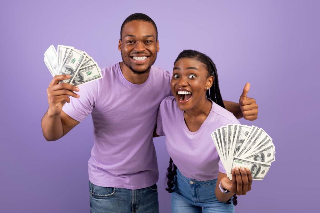 An excited couple holding cash, representing recent settlement payouts to consumers.