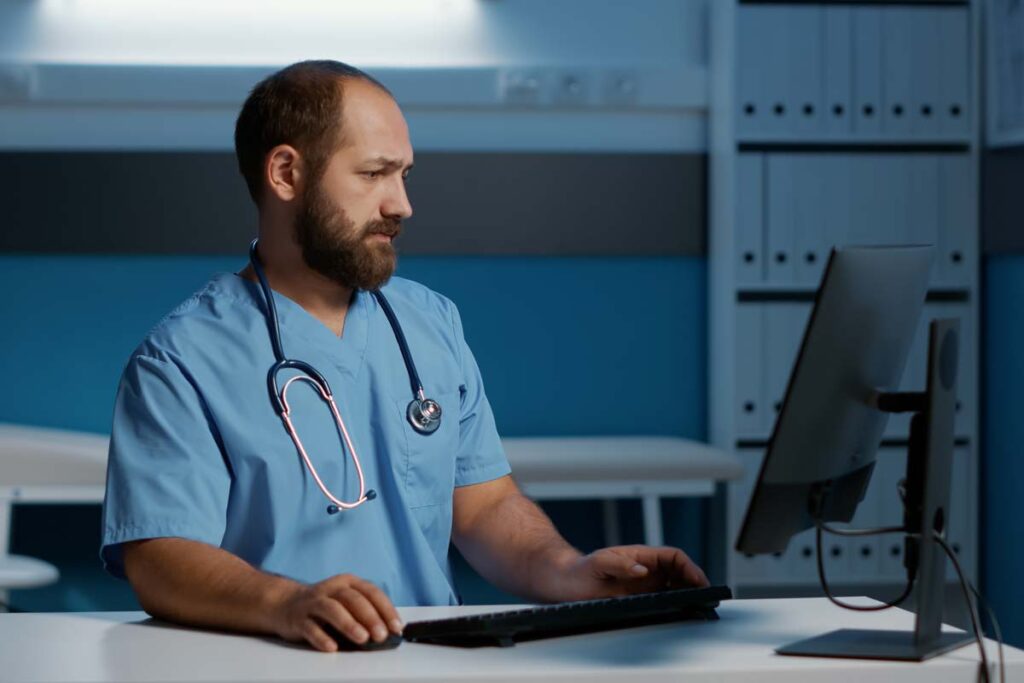 A male nurse using a computer, representing the US Fertility data breach class action lawsuit settlement.
