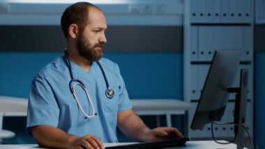 A male nurse using a computer, representing the US Fertility data breach settlement.