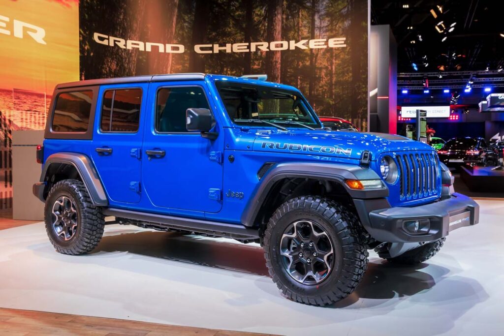 A blue 2023 Jeep Wrangler Plug In Hybrid Electric Vehicle at a car show, representing the Jeep recall.