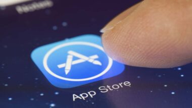 Close up of finger selecting Apple App store icon on smartphone display, representing the Apple iPhone web apps antitrust lawsuit.